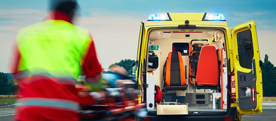 Ein Rettungssanitäter transportiert eine Person auf einer Trage zu einem Rettungswagen