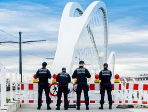 Vier Polizisten stehen vor einer Absperrung an einer Brücke